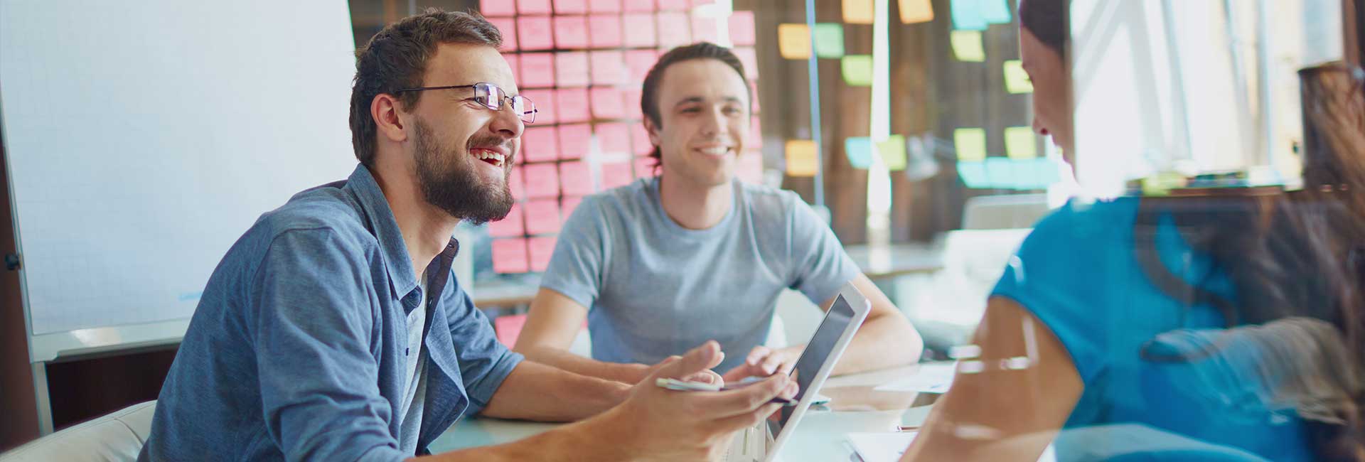Three team members sitting at a table discussing a project