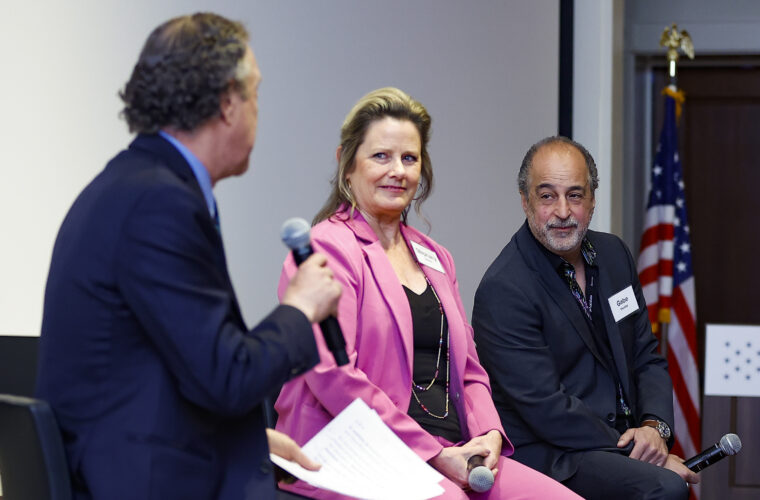 Three people sit on a panel discussing local journalism.