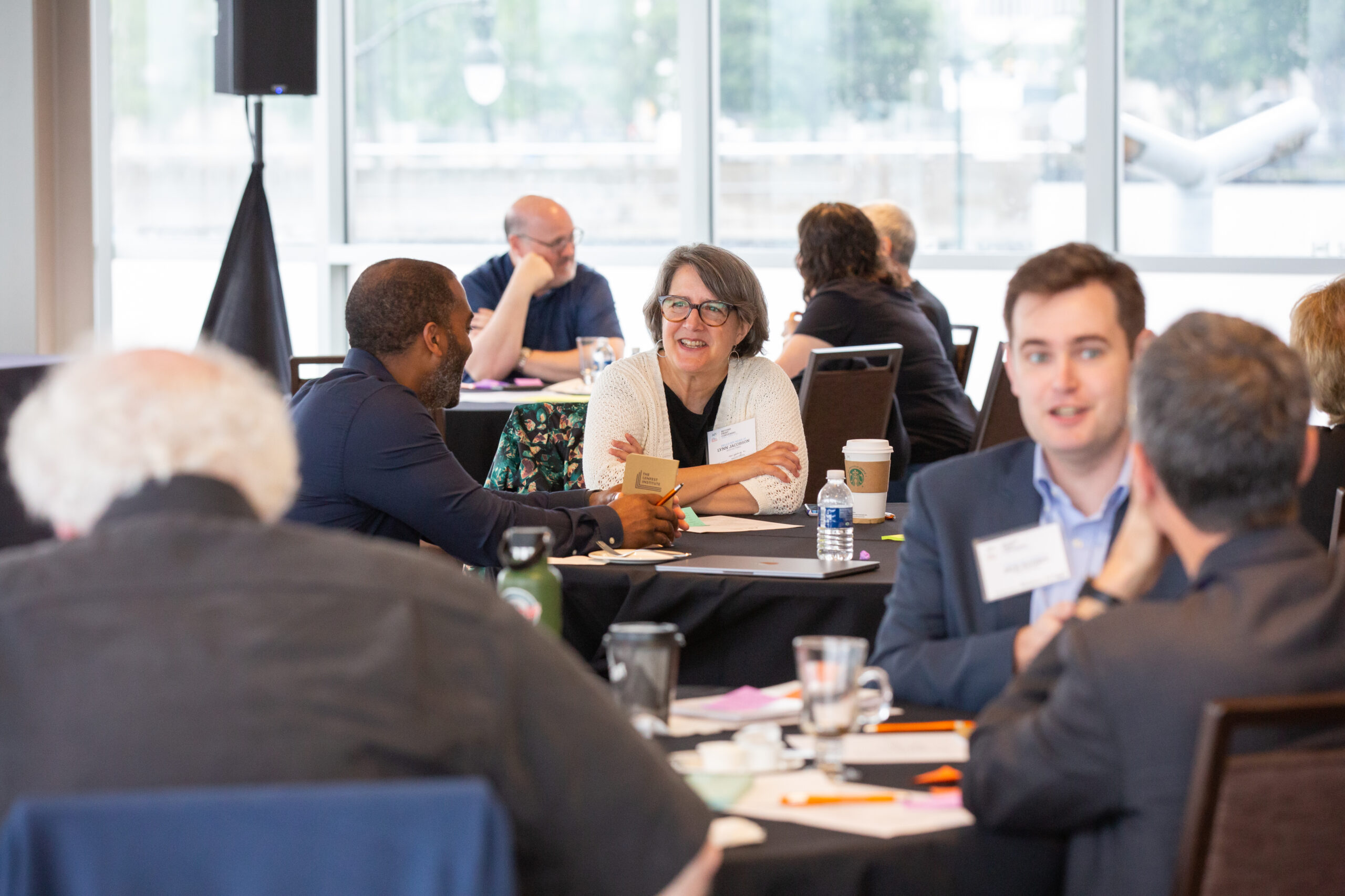 Participants at the Beyond Print Summit make small talk around tables with black table cloths.