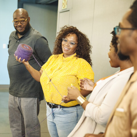 Members of the Philadelphia Media Founders Exchange hold purple string as part of an exercise.