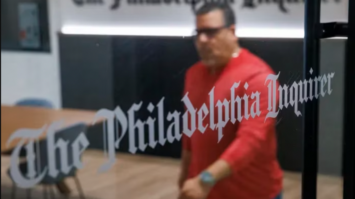 A man in a red shirt walks through The Philadelphia Inquirer newsroom