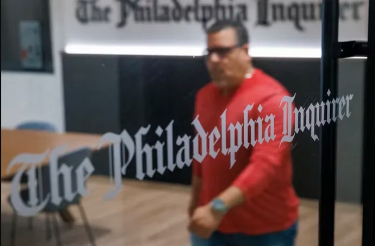 A man in a red shirt walks through The Philadelphia Inquirer newsroom