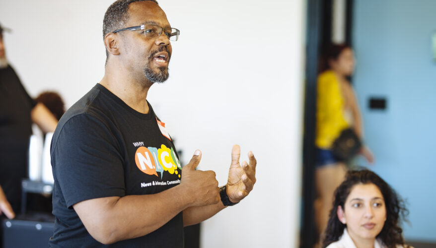 A man speaks wearing a N.I.C.E. T-shirt