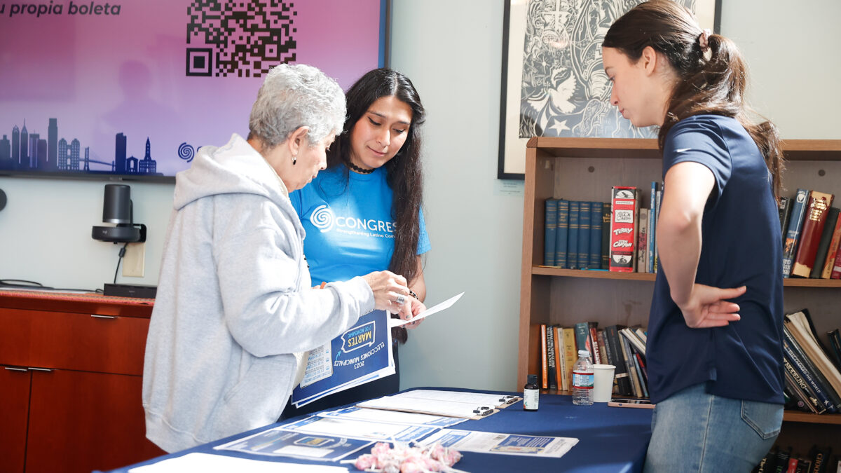 A Congreso employee in a teal shirt provides information to a voter.